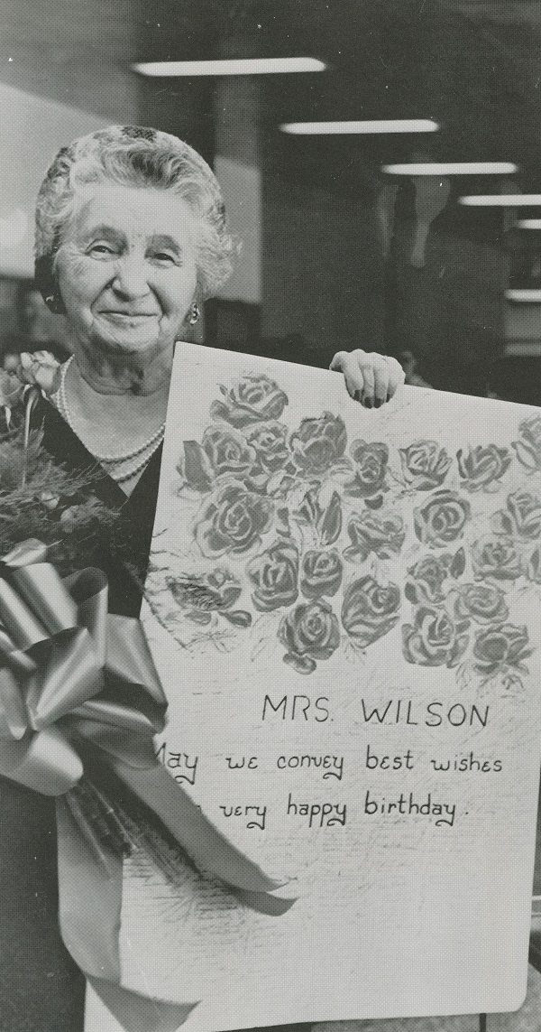 Mrs. Wilson holding a giant birthday card painted by OU students